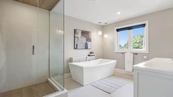 A modern bathroom with a glass shower enclosure, a freestanding bathtub, and a separate sink area.