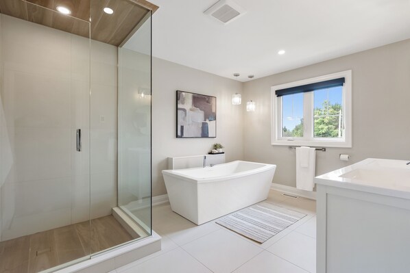 A modern bathroom with a glass shower enclosure, a freestanding bathtub, and a separate sink area.