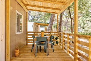 Eine Holzterrasse mit Tisch und Stühlen, umgeben von einem Holzgeländer, mit Blick auf eine natürliche Landschaft.