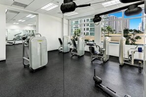 A gym with various exercise machines, large windows, and a view of buildings. - Brickell Condo w Pool, Parking & Balcony (Miami)