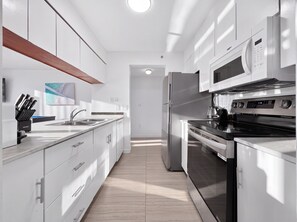 A modern kitchen with white cabinetry, stainless steel appliances, and a wooden countertop. - 2BR Brickell High-Rise - Pool, Gym & Game Room (Miami)