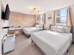 A hotel room with two beds, a desk, a TV, and a city view. - 2BR Brickell High-Rise - Pool, Gym & Game Room (Miami)