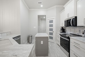 A modern kitchen with white cabinetry, a stainless steel range, and a microwave. - The Oak House - Love Street Collection 
Luxury New Build Near Love St. Park (Weatherford)