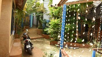 Una motocicleta estacionada en un jardín con una estructura azul y conchas colgantes.