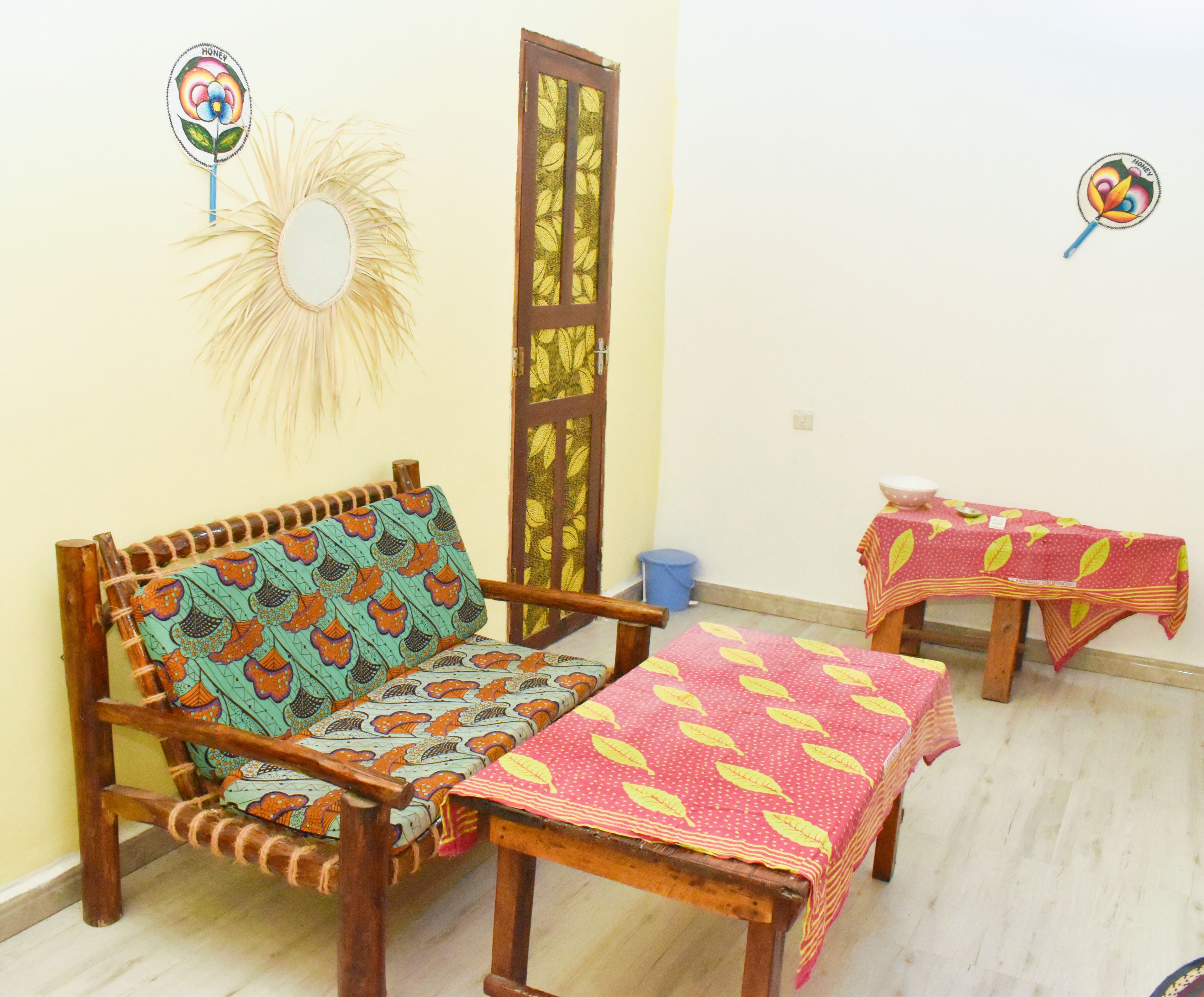 Habitación con sofá, una mesita, un espejo decorativo y una puerta con diseño de hojas.