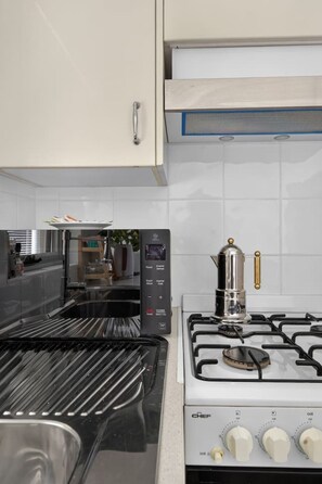 A kitchen with a gas stove, oven, and a built-in range hood. - 1BR 1BA | Near to Beach, Manly’s shops, Cafés and Restaurants (Manly)