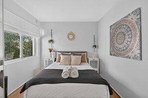 A bedroom with a bed, two bedside tables, a window, and a large abstract painting. - 1BR 1BA | Near to Beach, Manly’s shops, Cafés and Restaurants (Manly)