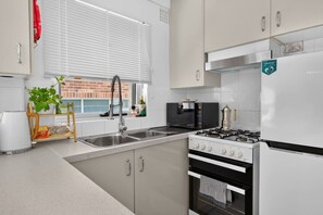 A modern kitchen with a gas stove, a microwave, and a sink. - 1BR 1BA | Near to Beach, Manly’s shops, Cafés and Restaurants (Manly)