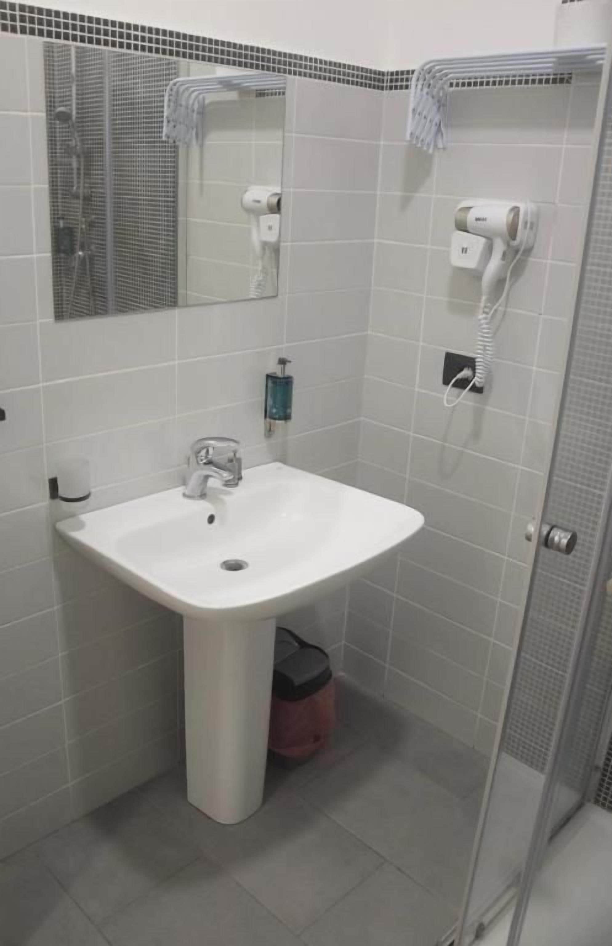 A bathroom with a white sink, a mirror, a towel rack, and a shower area.