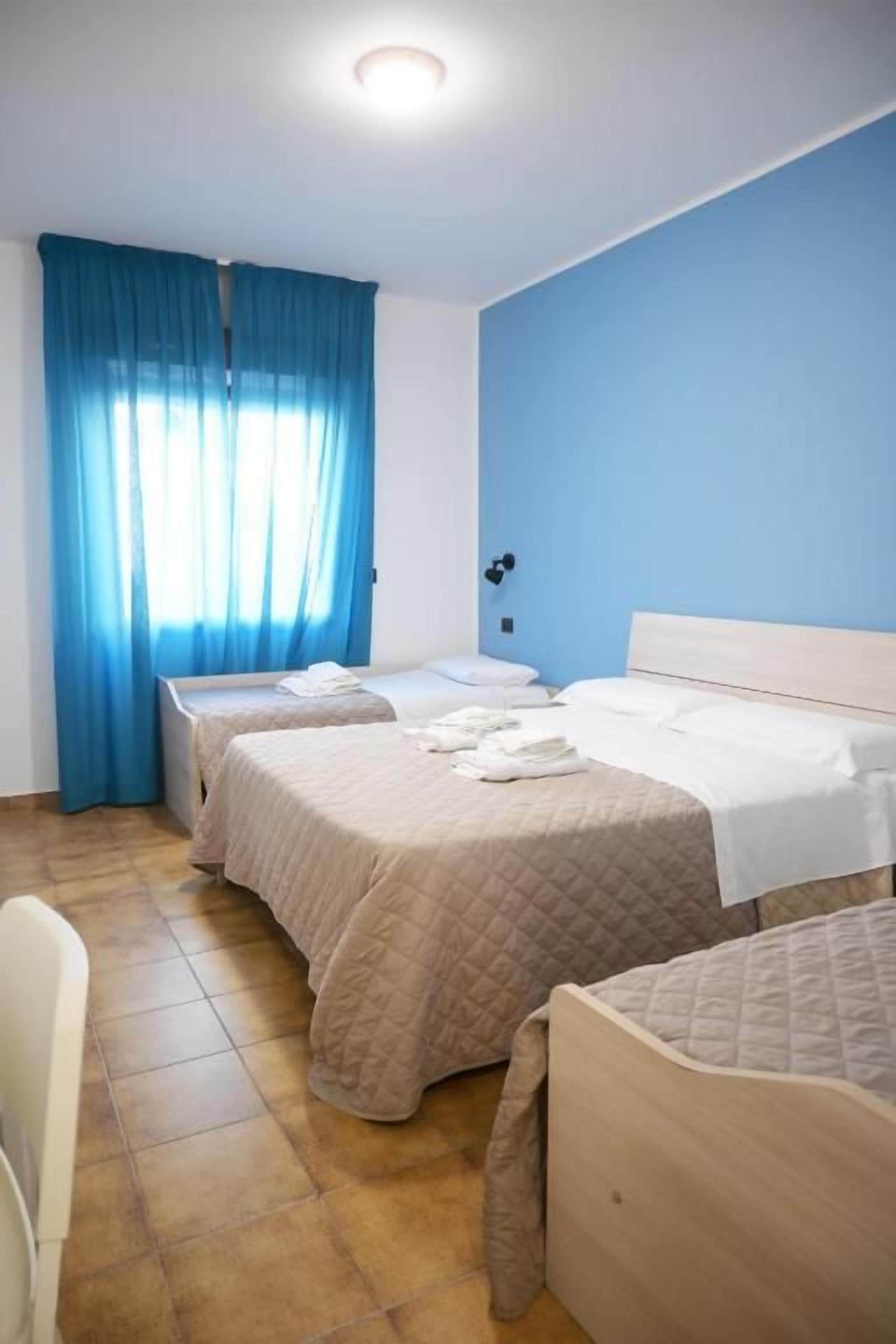 A hotel room with two beds, a chair, and a desk.