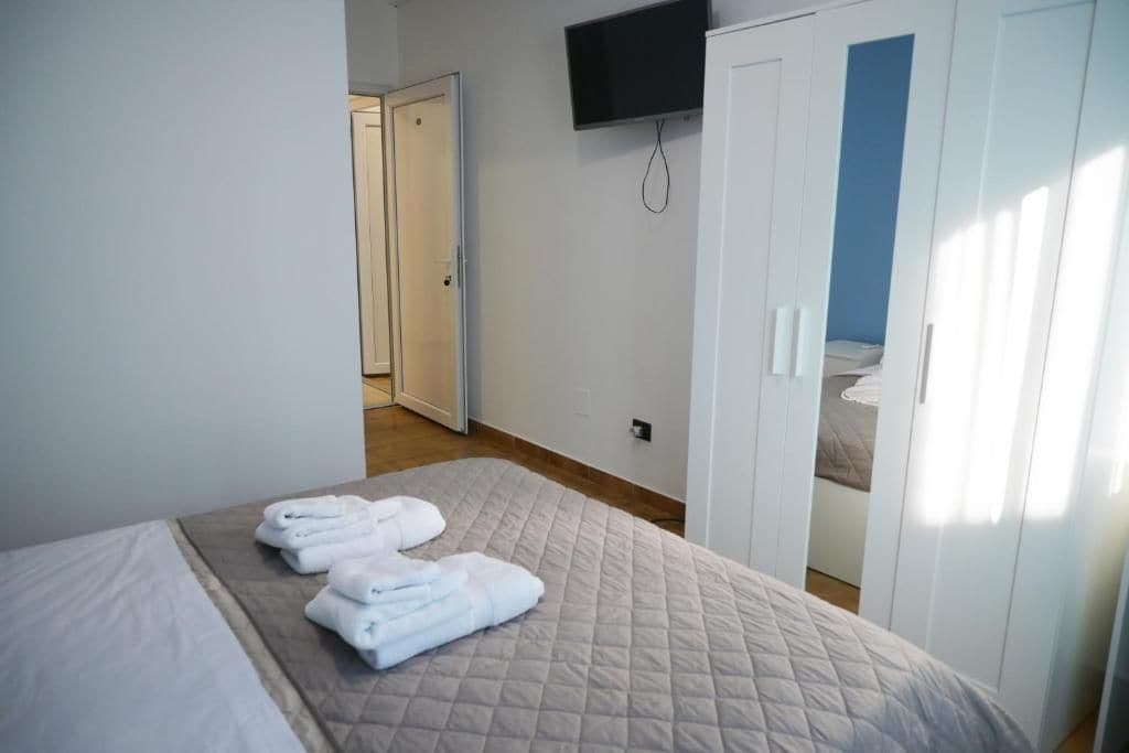 A hotel room with a bed, a TV mounted on the wall, and a wardrobe.
