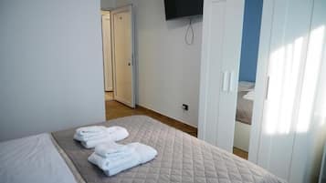 A hotel room with a bed, a TV mounted on the wall, and a wardrobe.