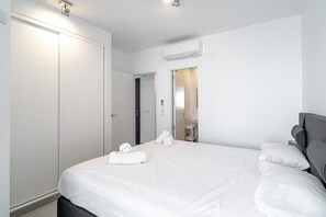 A hotel room with a large bed, a wardrobe, a bathroom with a sink and mirror, and an air conditioning unit. - Holiday Home in Nerja With Sea Views (Nerja)