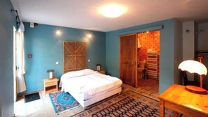 Ein Schlafzimmer mit einem Bett, Nachttischen, einer Lampe und einem gemusterten Teppich.