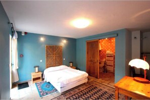 Un dormitorio con una cama, mesitas de noche, una lámpara y una alfombra estampada.