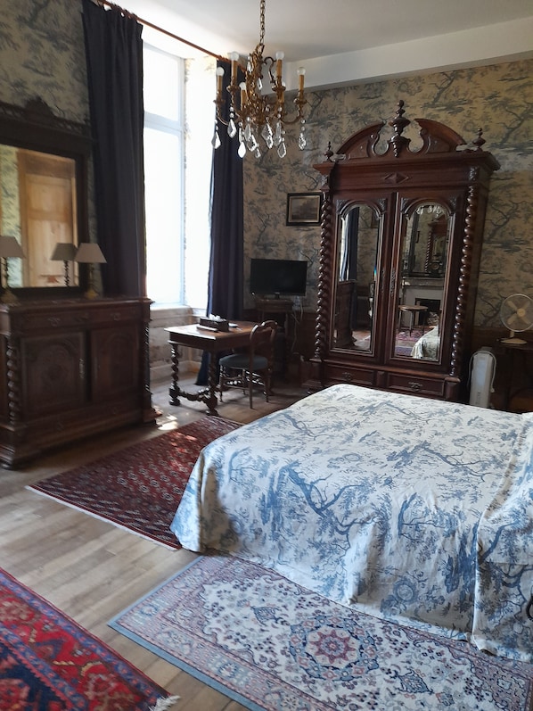 Un dormitorio con una cama grande, un aparador de madera, un escritorio, una televisión y un espejo.