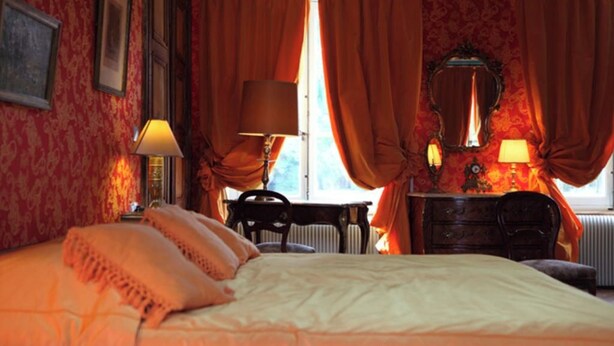 Ein Zimmer mit Bett, Schreibtisch, Stuhl und einem Vorhangfenster.