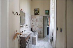 A bathroom with a marble wall, a sink, and a mirror.
