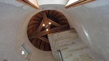 A circular room with a wooden ceiling structure and a small window with a cross symbol.