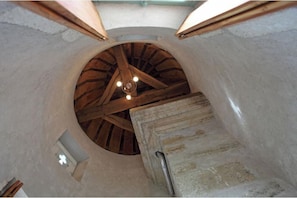Habitación circular con estructura de techo de madera y una pequeña ventana con un s ímbolo de cruz.