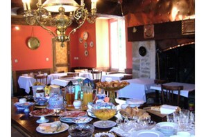 Un comedor con mesas dispuestas para el desayuno, una araña y una chimenea.