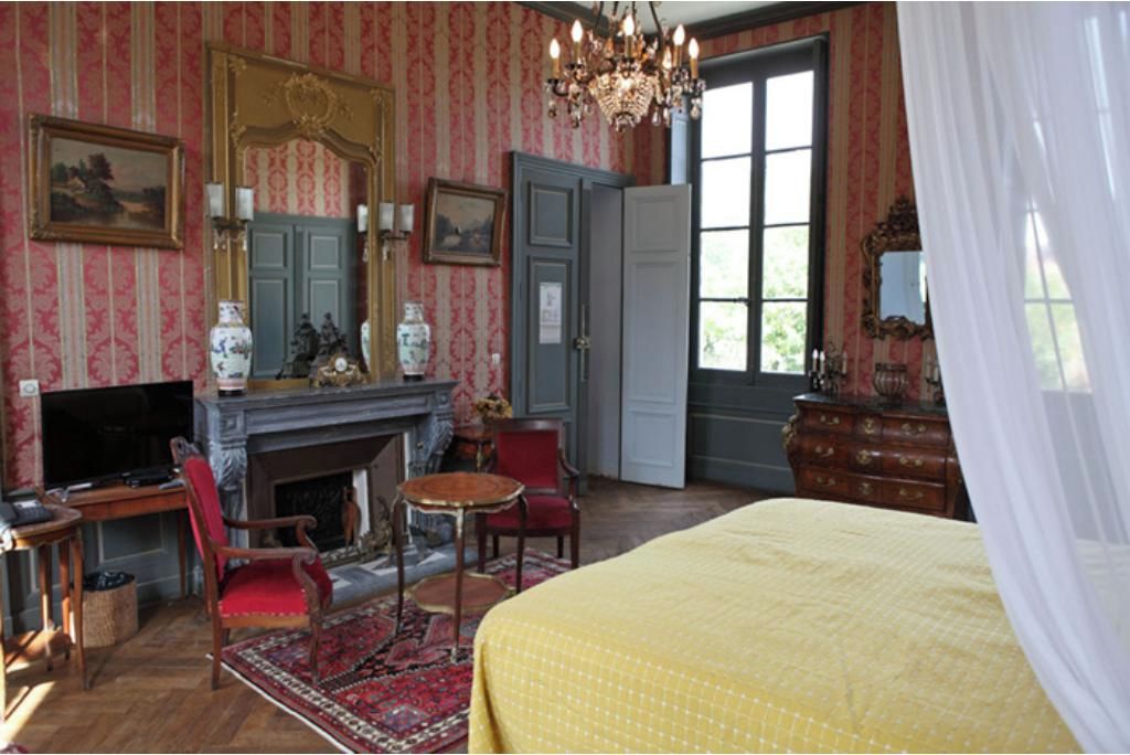 A room with a fireplace, a bed, a television, and a large window.