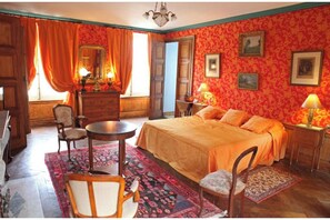 Una habitación con cama, cómoda, silla, mesa y lámpara.