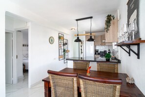 A modern kitchen with wooden cabinets, a central island, and hanging pendant lights. - Apartment in Nerja Near Burriana Beach (Nerja)