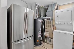 A compact kitchen with a stainless steel refrigerator, a water heater, and a white oven. - Charming 3BR/2BA condo near Hyde Park (Chicago)