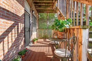A wooden deck with a brick wall, a metal gate, and potted plants. - Charming 3BR/2BA condo near Hyde Park (Chicago)