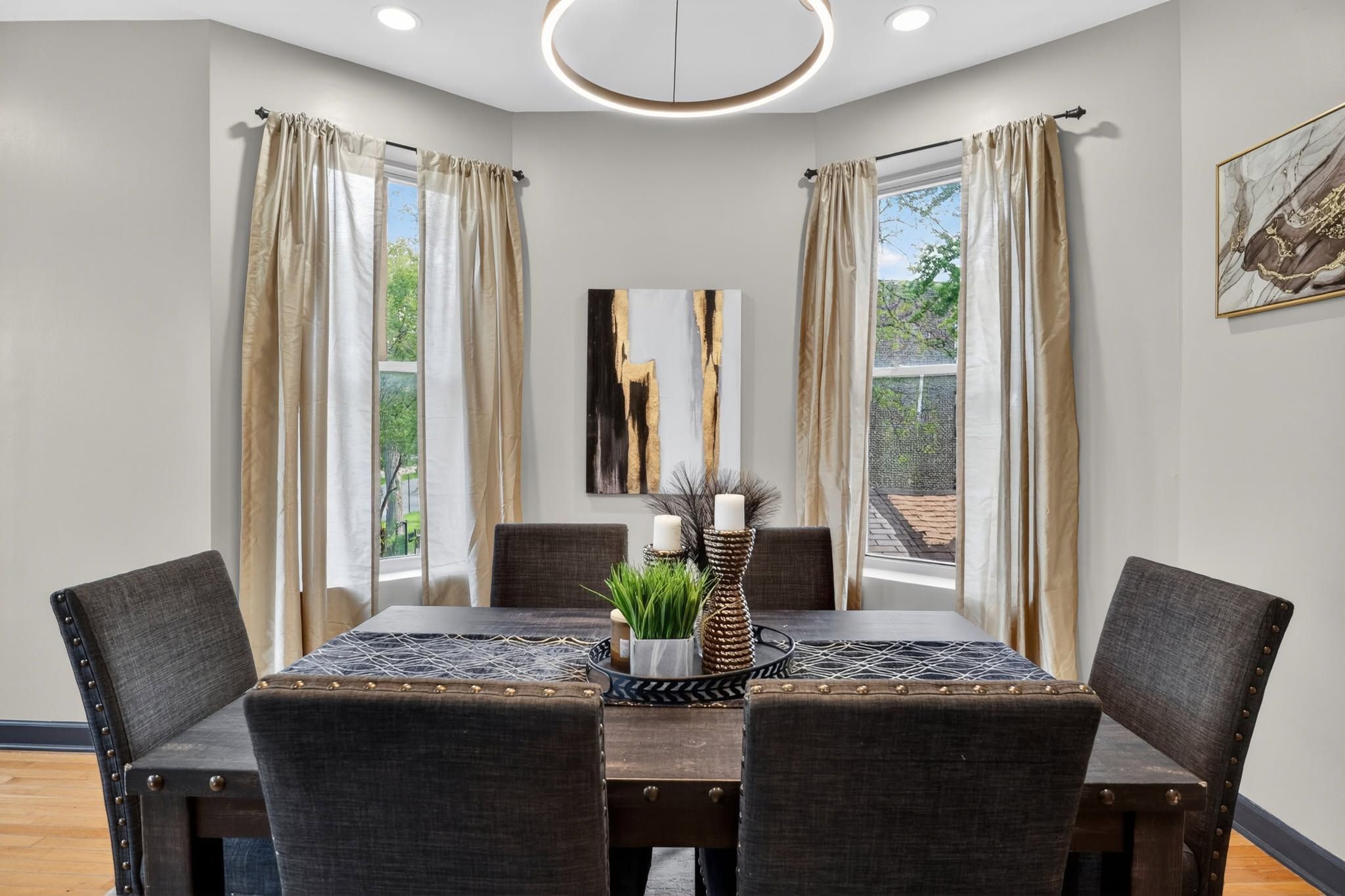 A dining area with a table set for four, surrounded by dark upholstered chairs.