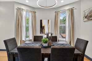 A dining area with a table set for four, surrounded by dark upholstered chairs. - Charming 3BR/2BA condo near Hyde Park (Chicago)