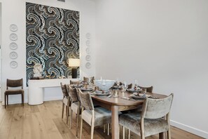 Zona pranzo con tavolo rotondo apparecchiata per sei persone, circondata da sedie.
