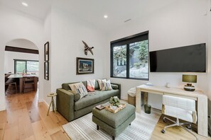 A modern living room with a green sofa, a dining area, and a large window with a view of trees. - 1061 Lowell Avenue #4 (Park City)