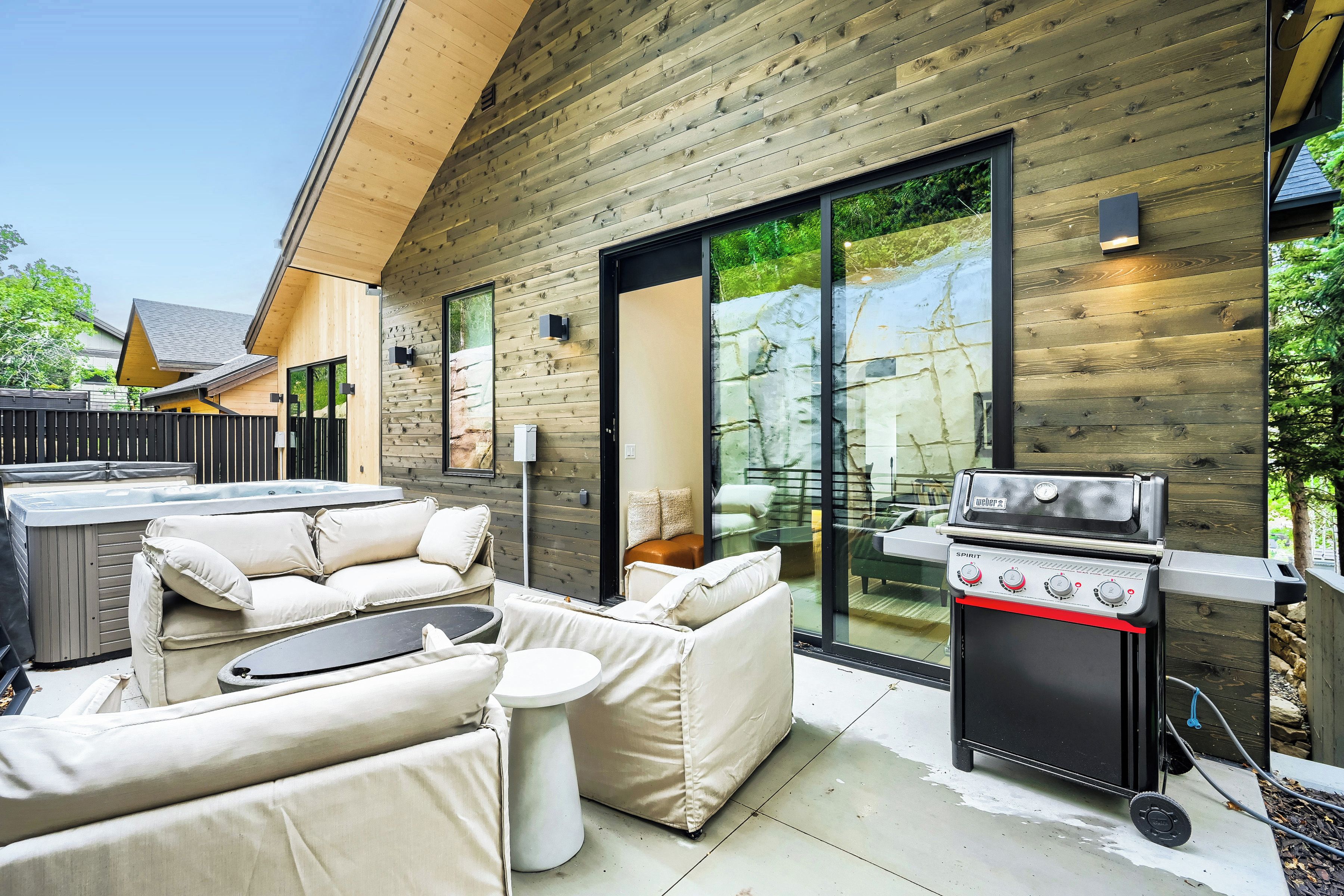 Un patio exterior con una parrilla, un conjunto de sofás y un jacuzzi.