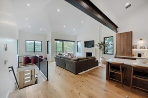 A spacious living area with a large sofa, a dining table, and a kitchen area with wooden cabinets. - 1061 Lowell Avenue #4 (Park City)