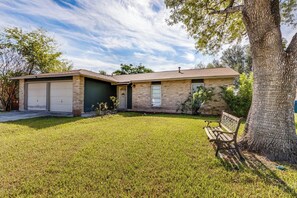 A two-story house with a garage, a front yard with a bench, and a tree. - Spacious & tranquil 4-bedroom house 20min Airport, Fort Sam &Downtown SanAntonio (San Antonio)