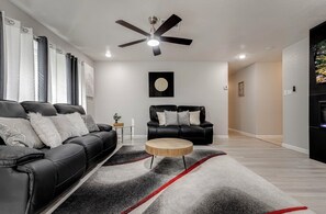 A modern living room with a black leather sofa, a wooden coffee table, and a ceiling fan. - Spacious & tranquil 4-bedroom house 20min Airport, Fort Sam &Downtown SanAntonio (San Antonio)