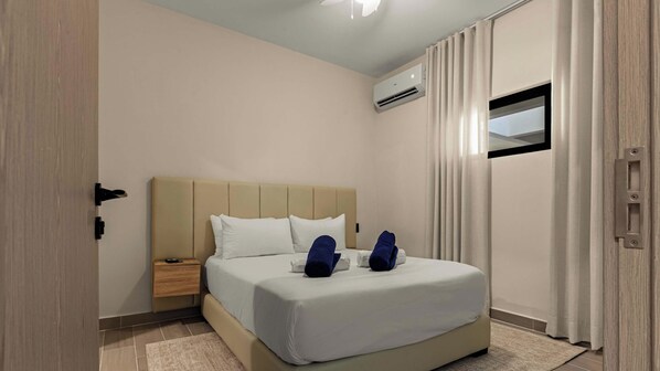 Une chambre d’hôtel avec un lit, une table de chevet, un appareil de climatisation et une fenêtre avec des rideaux.