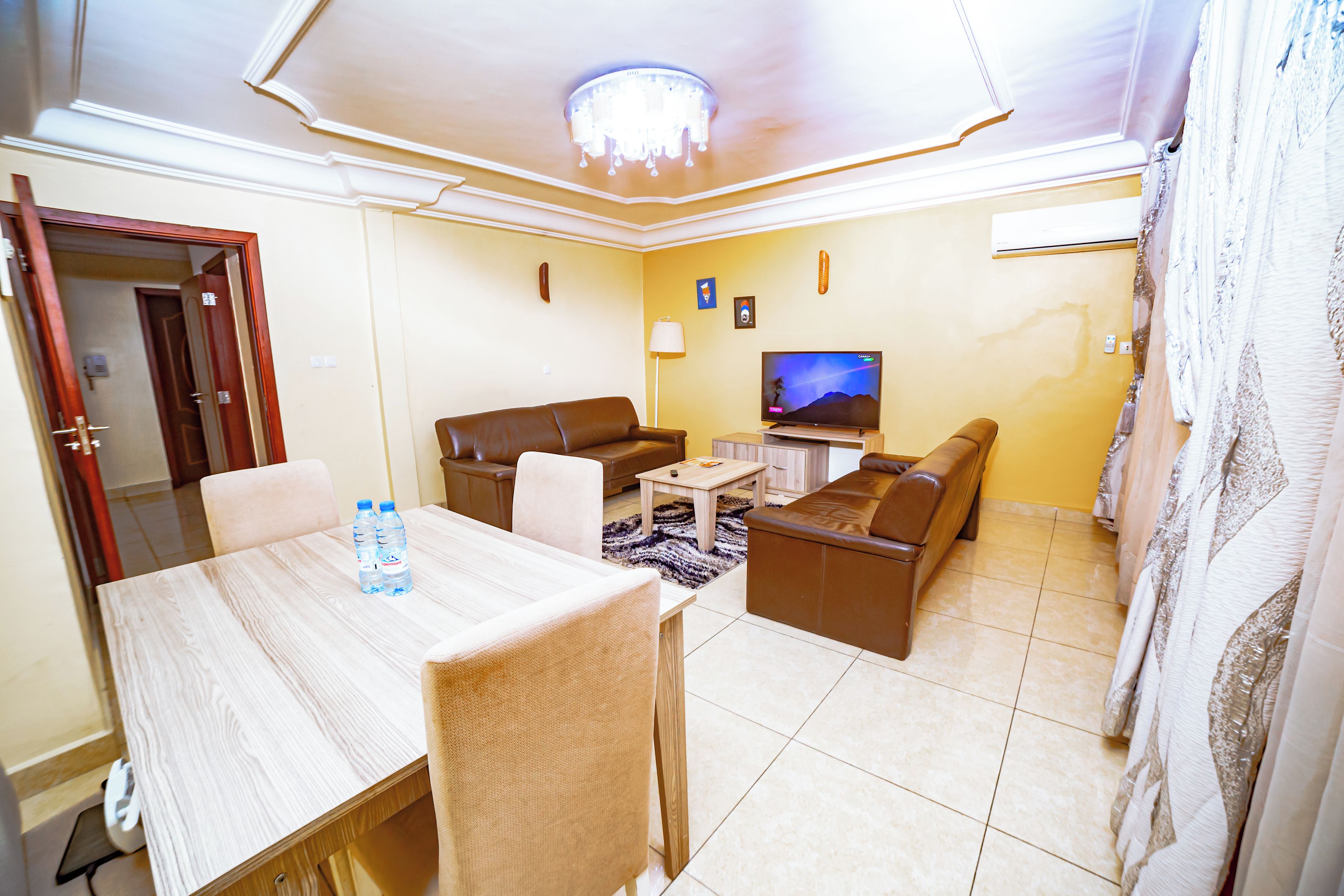 A living room with a television, sofa, and dining area with chairs and a table.