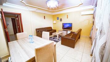 A living room with a television, sofa, and dining area with chairs and a table.