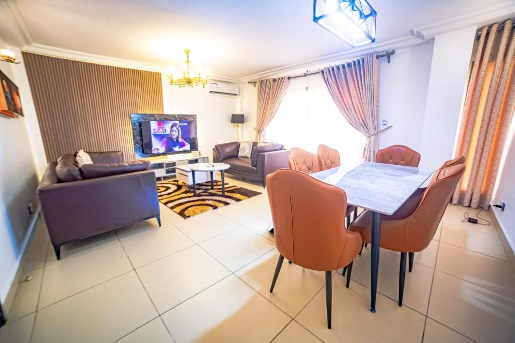 A living room with a sofa, a television, a dining table with chairs, and a patterned rug.
