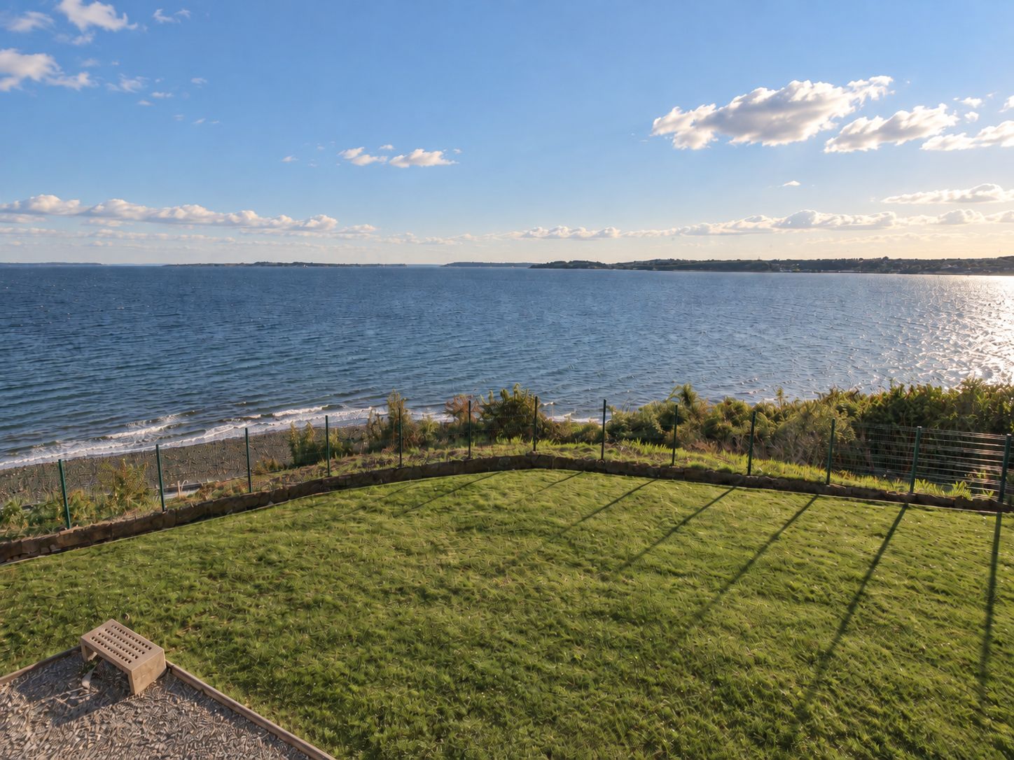 A grassy area with a view of the sea and a distant shoreline.