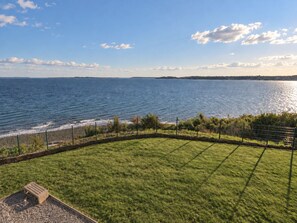 A grassy area with a view of the sea and a distant shoreline. - Cozy Apartment with a Spectacular Ocean View in Puerto Montt, Pelluco Beach (Puerto Montt)