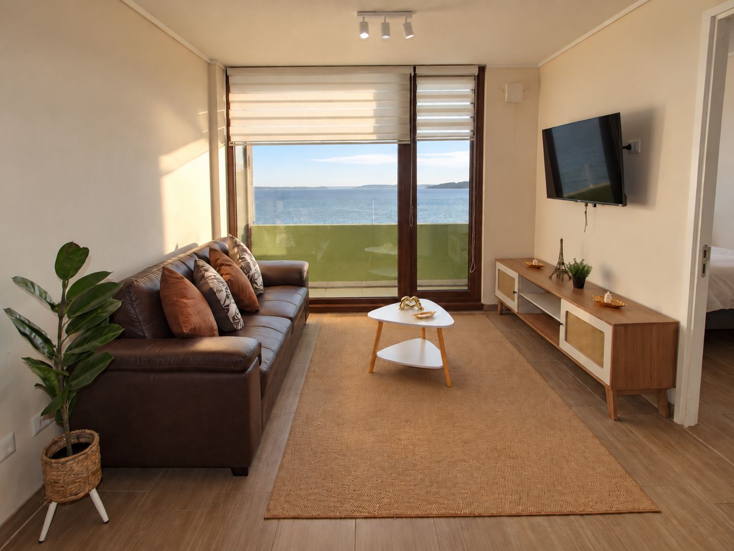 Un salon moderne avec un canapé, une table basse, un téléviseur et une vue sur la mer.