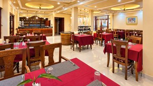 A restaurant with multiple tables, chairs, and a bar area. - The Orchid Phuentsholing (Phuntsholing)