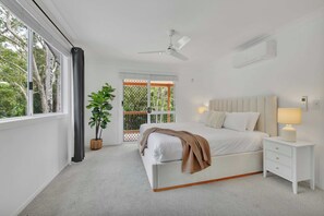 A bedroom with a bed, bedside tables, a ceiling fan, and a view through a window. - Tropical 3BR Retreat  Currumbin Waters (Currumbin Waters)