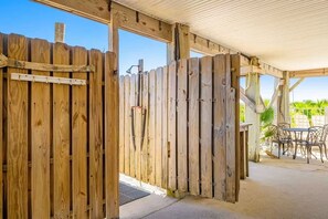 Een houten omheining met een poort, een overdekt terras en tuinmeubilair.