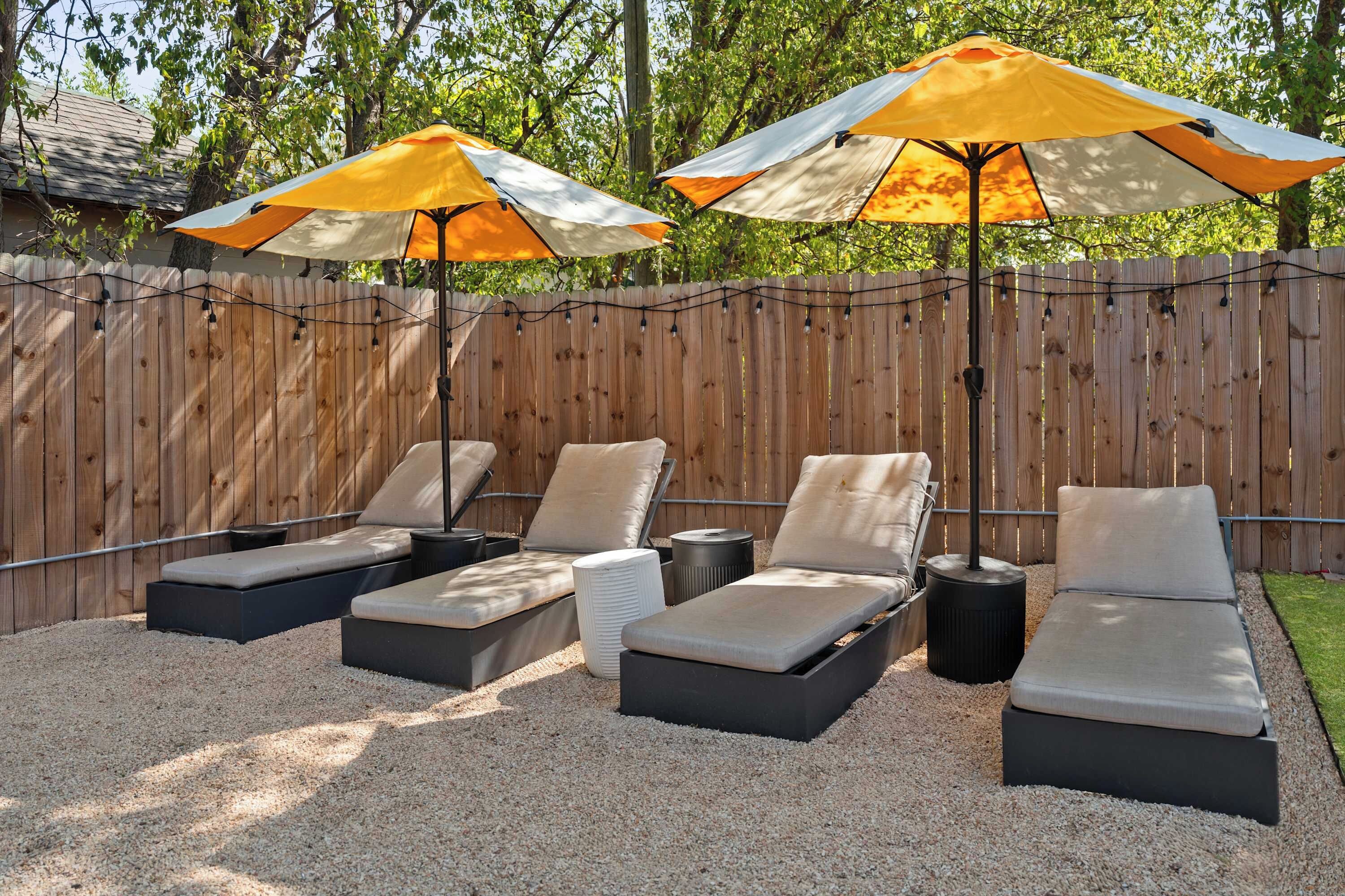 Een terras met vier lounge stoelen en twee parasols.