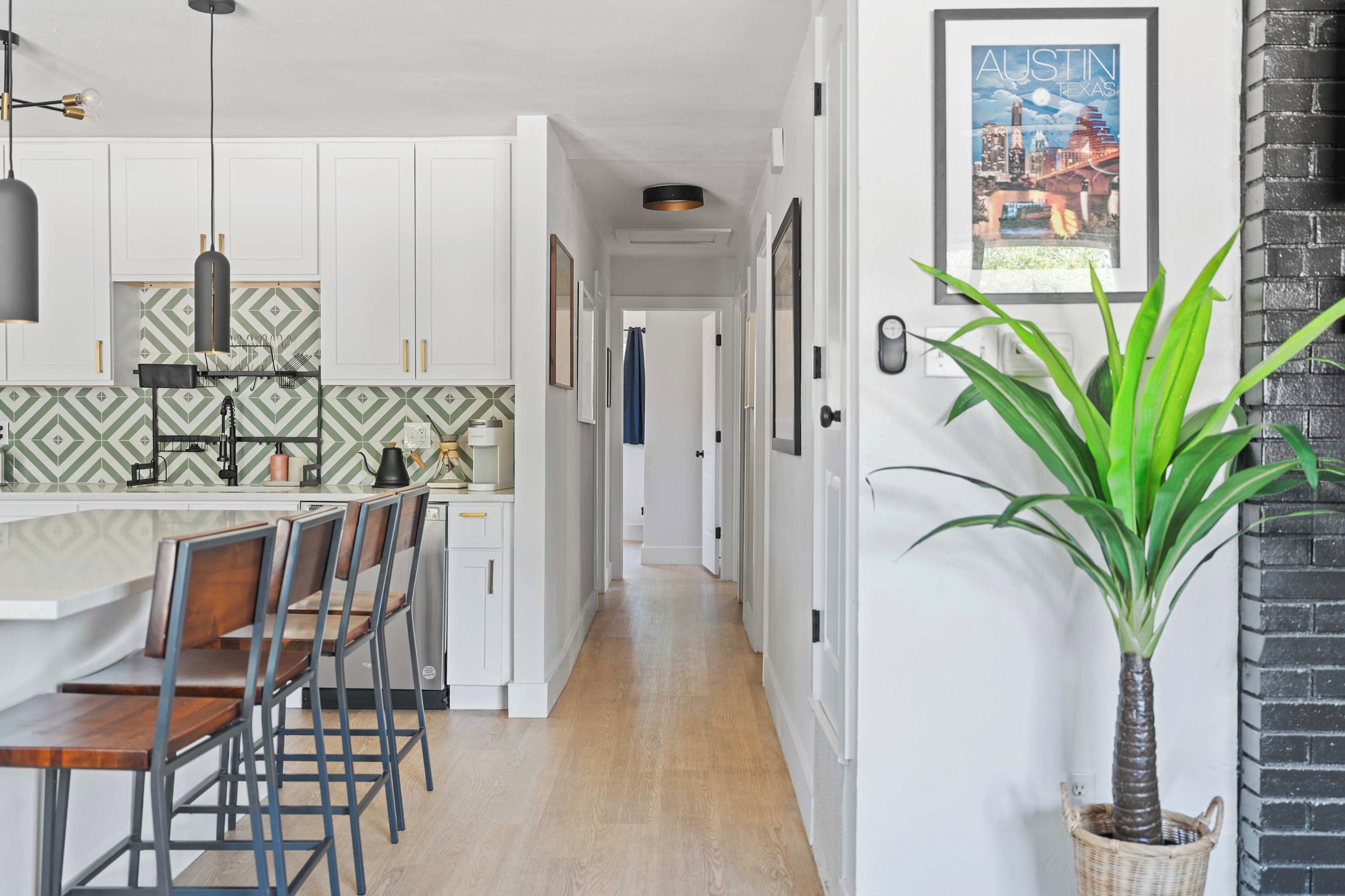 A modern kitchen with white cabinets, a patterned backsplash, and a dining area with bar stools.